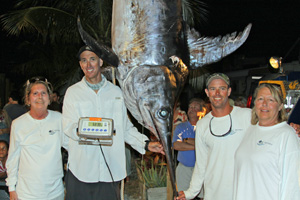 From left, Katherine MacMillan, Billy Rabito Jr., Mike Driskell and Anna Woodruff pose next to the mammoth swordfish that Driskell reeled in. 
